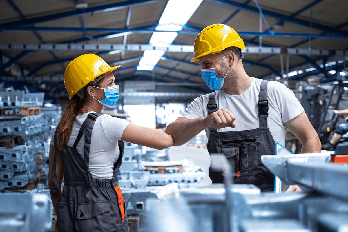 How Do States Evaluate COVID-Related Workers’ Compensation Claims? Factory workers practice safe COVID-19 procedures
