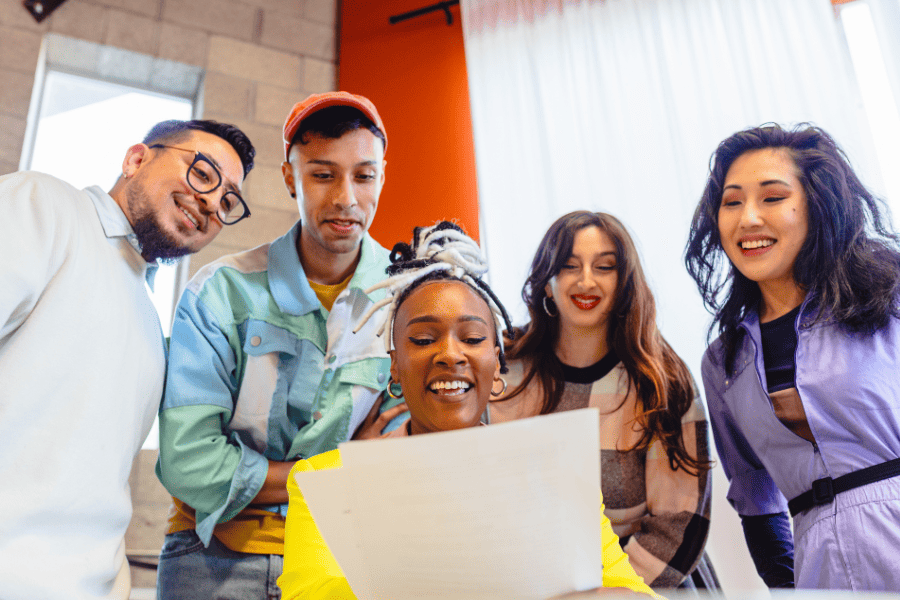 a group of casually dressed office workers examaning a printed document